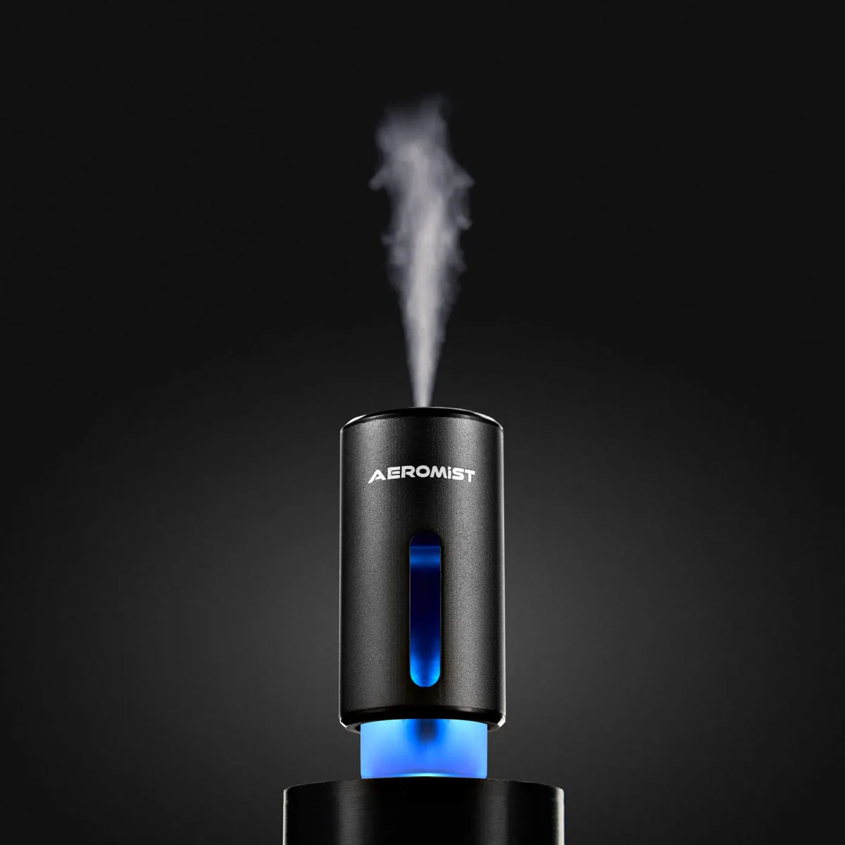 AeroMist diffuser on its base releasing a plume of mist, blue LED glowing